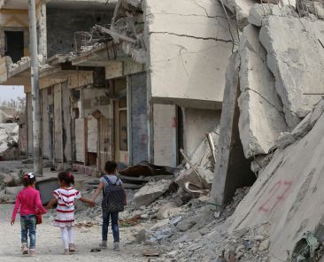 Syrian children walk past debris while heading to school on the second day of the new school year on October 6, 2015 in the Syrian Kurdish town of Kobane. (DELIL SOULEIMAN / AFP)