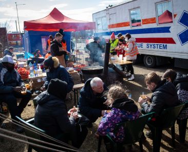 Slovak volunteers hand out food to Ukrainian refugees at the Slovak-Ukrainian border in Vysne Nemecke, Slovakia, on March 2, 2022. - The number of refugees fleeing the conflict in Ukraine has surged to nearly 836,000, United Nations figures showed on March 2, 2022, as fighting intensified on day seven of Russia's invasion. (Photo by PETER LAZAR / AFP)