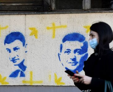 A woman walks past stencil paintings depicting Kyiv's mayor Vitali Klitschko (L) and Ukraine's President Volodymyr Zelensky on a building in downtown Podgorica on March 9, 2022. (AFP / SAVO PRELEVIC)