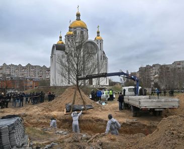 Journalists gather as bodies are exhumed from a mass-grave in the grounds of the St. Andrew and Pyervozvannoho All Saints church in the Ukrainian town of Bucha, northwest of Kyiv on April 13, 2022. (Photo by Sergei SUPINSKY / AFP)