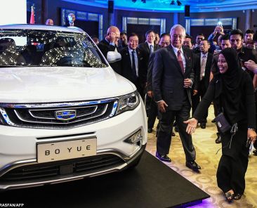 Malaysia's Prime Minister Najib Razak (C) walks next to first public viewing of the Geely Boyue SUV car after the signing ceremony between DRB-HICOM Berhad and Zhejiang Geely Holding Group in Kuala Lumpur on June 23, 2017. Chinese auto giant Geely will inject cash and one SUV product for the 49.9 percent stake it had agreed to acquire in loss-making carmaker Proton to gain access to the booming Southeast Asian market, officials said on June 23. (Photo by Mohd RASFAN / AFP)