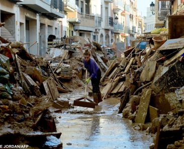 A woman works to clean mud among debris in a street of Paiporta, south of Valencia, eastern Spain, on November 6, 2024, in the aftermath of deadly floods. - Spain announced an aid package worth 10.6 billion euros ($11.5 billion) to rebuild regions devastated by its worst floods in a generation that have killed 219 people. (Photo by JOSE JORDAN / AFP)