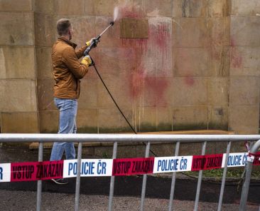 An employee of the Russian Embassy to the Czech Republic cleans the Embassy's sign on a wall, smeared in blood-red color in protest against the Russian invasion of Ukraine, on April 1, 2022 in Prague. (Photo by Michal Cizek / AFP)